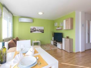 a living room with green walls and a white table at Apartment Salvagno - Two Bedroom Apartment with Balcony and Sea View in Punat