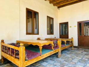 a room with two wooden beds and a table at Dervish Hostel in Bukhara