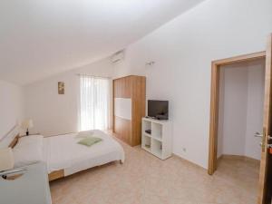 a white bedroom with a bed and a television at Apartments Bandalo - Standard Studio Apartment in Podstrana