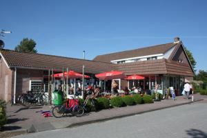 een gebouw met rode parasols en fietsen die voor het gebouw staan bij Camping 't Veerse Meer in Wolphaartsdijk