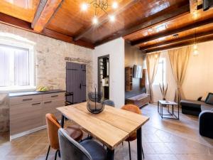 a kitchen and living room with a wooden table and chairs at Stone House Prapatna-Two Bedroom Holiday Home with Swimming Pool in Smokvica