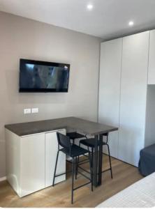 a room with a table and a tv on a wall at Monolocale nuovo arredato vista mare in Valverde