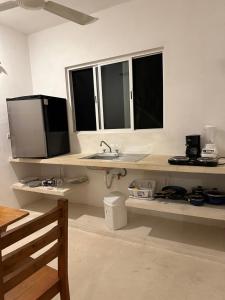 a kitchen with a counter with a sink and two windows at Habitación Coco in Holbox Island