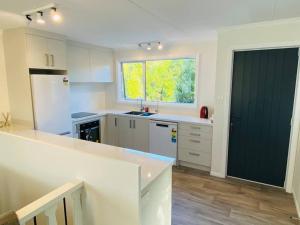 a kitchen with white cabinets and a green door at Kaka Point Beach House in Kaka Point
