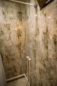 a shower in a bathroom with a stone wall at Tiran in Getapʼ