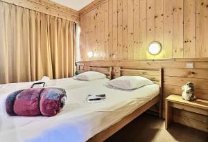 sypialnia z 2 łóżkami i drewnianą ścianą w obiekcie Résidence Le Bec Rouge - Appartement de charme 3 pièces 8 personnes à Tignes ski aux pieds et proche des commerces dans le quartier du Lac MAE-1993 w mieście Tignes