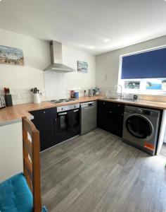 a kitchen with a washer and dryer in it at Corner Cottage Mevagissey in Mevagissey +22 photos