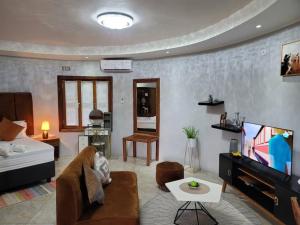 een woonkamer met een bank en een flatscreen-tv bij Hasna lodge in Ruashi