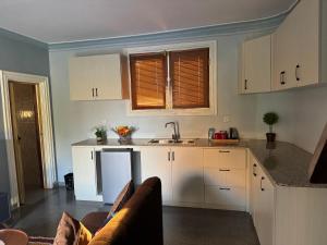 een keuken met witte kasten en een spoelbak bij Hasna lodge in Ruashi