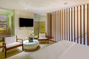 a bedroom with a bed and two chairs and a tv at Apple Motel ( Adults Only ) in São Paulo