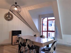 a dining room with a table and chairs and a clock at Appartement cosy en duplex une chambre in Lamballe