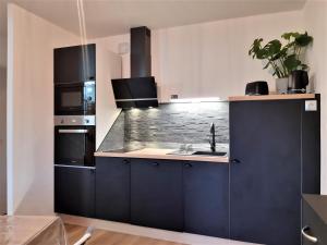 a kitchen with black cabinets and a sink at Appartement cosy en duplex une chambre in Lamballe +1 photo
