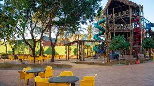 a playground with tables and chairs and a slide at Hot Beach Celebration in Olímpia