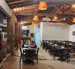 a dining room with tables and chairs and lights at Santa Areia Lençóis Pousada in Santo Amaro