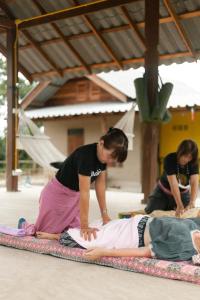 a woman is laying on a yoga mat with another woman at Little Forest Chiang Mai in Chiang Mai
