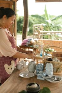 a woman is making a vase on a table at Little Forest Chiang Mai in Chiang Mai