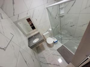 a white bathroom with a toilet and a shower at Pousada Suítes 590 in Penha