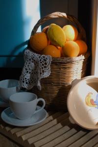 a basket of fruit sitting on a table with cups at La Piccola Bellezza in Pisticci +48 photos