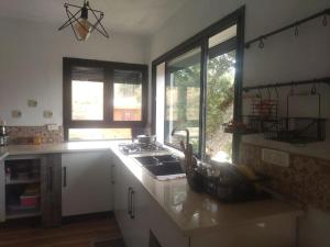 a kitchen with a sink and a stove and windows at DarAlRayhan in Aïn Draham