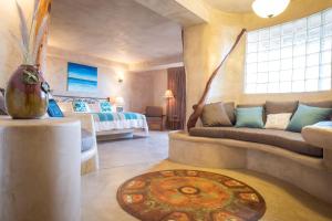 a room with a bed and a couch and a table at Alegria Suites Centro Historico in Todos Santos
