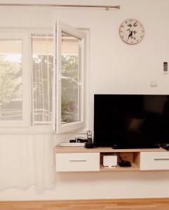 a living room with a tv and a clock on the wall at Holiday House Maya in Mostar