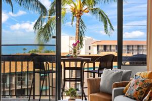 einen Balkon mit einem Tisch, Stühlen und einer Palme in der Unterkunft Maui Vista 3403 in Kihei