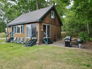 a small cabin with chairs and a grill in a yard at Cozy Cove Cottage Winter Rental Available in Belgrade