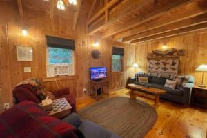 a living room with a couch and a tv in a cabin at Cozy Cove Cottage Winter Rental Available in Belgrade