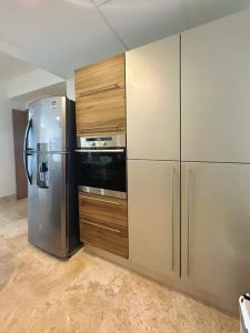 Una cocina con refrigerador de acero inoxidable y gabinetes de madera. en Moderno Departamento de Lujo en Cancún, en Cancún 34 fotos más