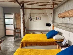 a bedroom with a bed with yellow sheets and blue pillows at Departamentos Maya in Isla Mujeres