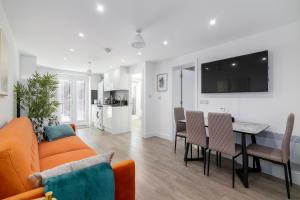 a living room and kitchen with a couch and a table at Flat in Queens Park in London
