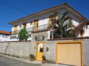 a white house with orange doors and a palm tree at Pousada Água Viva in Paraty