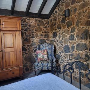 a bedroom with a stone wall and a chair with a pillow at Rural escape w/stunning views, jacuzzi and sauna in La Laguna