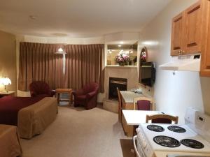 a living room with a kitchen and a living room with a stove at New Imperial Suites in Whitecourt