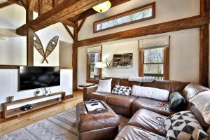 a living room with a leather couch and a flat screen tv at Wobbly Cabin - 2 Bedroom - Charming Ski Home - Fireplace - WiFi - Close to Resort in Killington