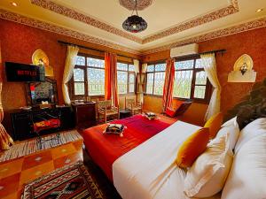 a bedroom with a large bed and a television at Riad Chay & Boutique in Ouarzazate