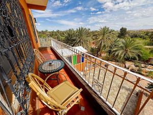 a balcony with a table and chairs and palm trees at Riad Chay & Boutique in Ouarzazate