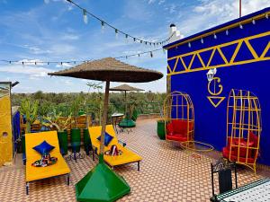 a patio with tables and chairs and an umbrella at Riad Chay & Boutique in Ouarzazate