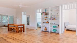 a white room with a table and a book shelf at Welcome To Queenslander By The Sea in South Golden Beach