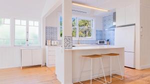 a kitchen with white cabinets and blue tiles at Welcome To Queenslander By The Sea in South Golden Beach