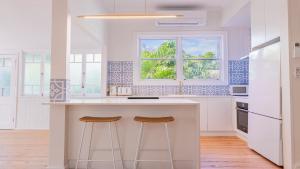 a kitchen with a island with two stools at Welcome To Queenslander By The Sea in South Golden Beach