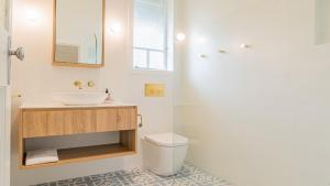 a white bathroom with a sink and a toilet at Welcome To Queenslander By The Sea in South Golden Beach