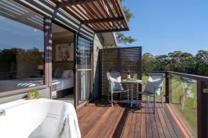 a deck with a bed and a table and chairs at Hermitage Lodge in Pokolbin