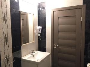ein Badezimmer mit einem Waschbecken, einem Spiegel und einer Tür in der Unterkunft Hotel Mic in Bukarest