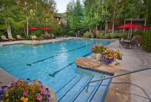 una gran piscina con flores, mesas y sombrillas en Aspenwood 311 condo, en Edwards