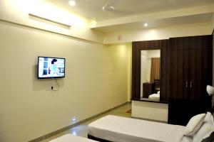 a living room with a tv on the wall at Hotel Gulmohar Pride in Ahmadnagar