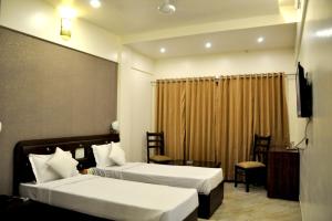 a hotel room with two beds and a television at Hotel Gulmohar Pride in Ahmadnagar