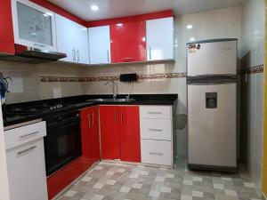 a kitchen with red cabinets and a white refrigerator at Arama Casa Artesanal in Paipa