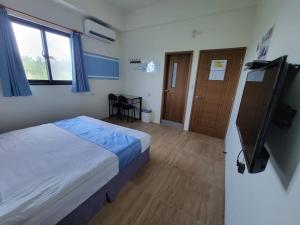 a bedroom with a bed and a tv in it at 玩樂夷夏民宿 in Magong