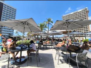 eine Gruppe von Personen, die an Tischen mit Sonnenschirmen sitzen in der Unterkunft Salinas Premium Resort in Salinópolis